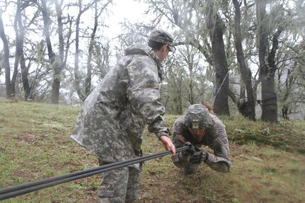 U.S. Army Reserve soldier Sfc. Corey Stevick crosses the rope crawl while Sfc. Sb Decker is a safety for him while he crosses during the Best Warrior Competition Fort Hunter Liggett Calif. on February 7, 2017. The rope crossing was one of the most difficult obstacles during the course according to the candidates. 