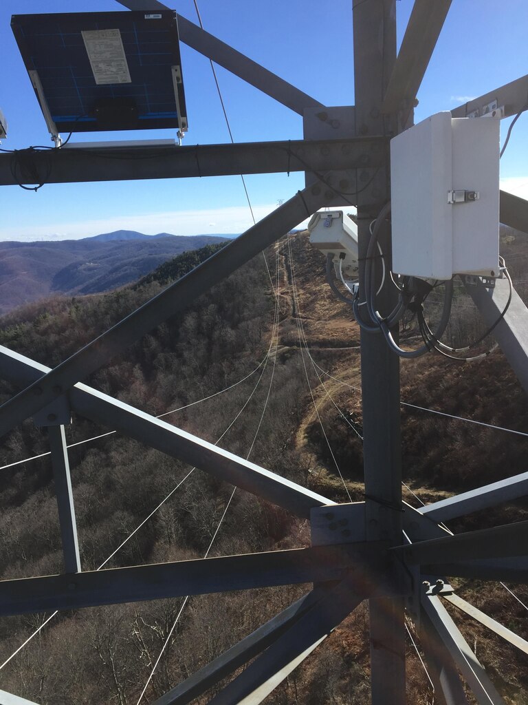 This photograph shows one of the AEP monitoring sites. Each site is equipped with three interconnected components – from left, a solar panel, web camera and data acquisition system (white box) that collects data from an anemometer and temperature/humidity sensor. The site provides daytime images and 24/7 data of meteorological events at the site during the cold weather months.
