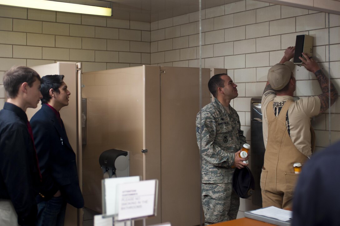 U.S. Staff Sgt. Tyler Wiseman and Air Force Staff Sgt. Dakoda Riddle, 17th Security Forces Squadron K9 handlers, install sodium chlorite decoy inside the base theater bathroom on Goodfellow Air Force Base, Texas, Feb. 8, 2017. The sodium chlorite is a common chemical powder used to make household bombs. K9s are trained in smelling out this chemical and others in the smallest quantities. (U.S. Air Force photo Senior Airman Scott Jackson/Released)