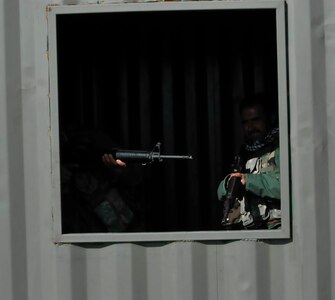 Peshmerga soldiers peer out from the shadows after entering and clearing a building during urban operations training near Erbil, Iraq. Dutch and Norwegian soldiers, part of the Kurdistan Training Coordination Center, oversaw the day's training which included individual movement techniques, counter IED and entry control point procedures. The KTCC is a multi-national coalition dedicated to the training, advising and assistance of Kurdish forces to defeat ISIL in Iraq.