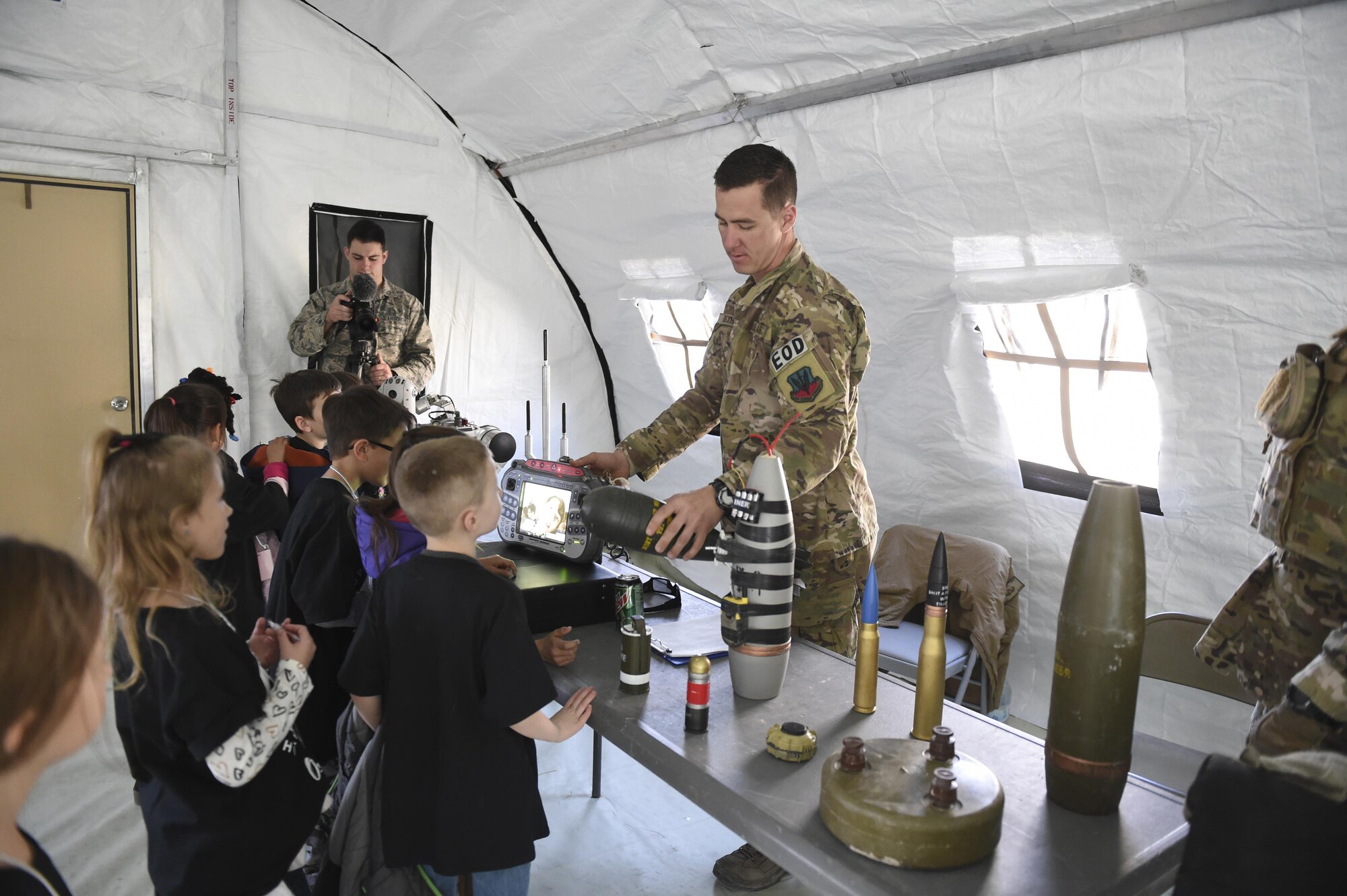 Staff Sgt. Evan Dieckhoff, 49th Civil Engineer Squadron Explosive Ordnance Disposal technician, holds a plastic mock artillery projectile to a student during Operation Kids Investigating Deployment at Holloman Air Force Base, N.M., Feb. 3, 2017. Operation KID is an annual event allowing children of military members to acquire a better understanding of what their parents go through prior to a deployment. Military children were given a walk around the Basic Expeditionary Airfield Resources compound to see a mock deployment site, have a mission brief, paint their faces, try on Mission Oriented Protective Posture gear, and learn about different equipment including the opportunity to see a robot demonstration from Holloman’s EOD unit. (U.S. Air Force photo by Staff Sgt. Stacy Jonsgaard)