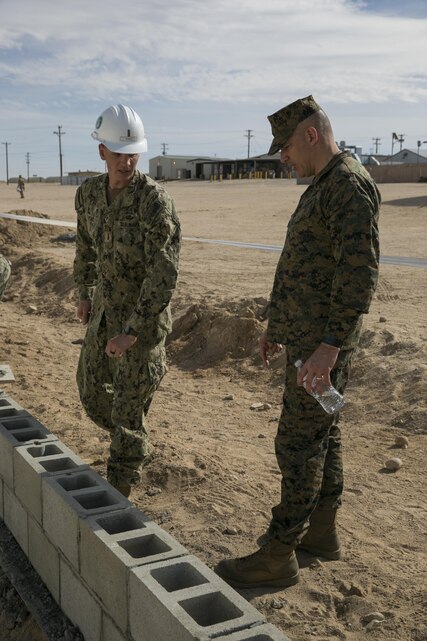Ensign Frank Sysko, detachment Twentynine Palms Officer in Charge, Naval Mobile Construction Battalion 3, and Brig. Gen. William F. Mullen III, Combat Center Commanding General, tour the construction of the diversion walls in progress at Camp Wilson aboard Marine Corps Air Ground Combat Center, Twentynine Palms, Calif., Feb. 2, 2017. NMCB 3 is in Camp Wilson for three weeks working on the construction of displacement walls and K-Span units for their upcoming deployment in April. (U.S. Marine Corps photo by Lance Cpl. Dave Flores)