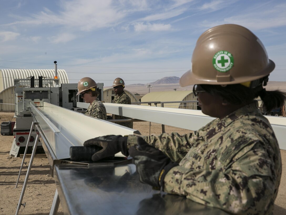 U.S. Navy Seabees with Naval Mobile Construction Battalion 3 prepare sheets of metal while constructing K-Span units at Camp Wilson aboard Marine Corps Air Ground Combat Center, Twentynine Palms, Calif., Feb. 2, 2017. NMCB 3 is in Camp Wilson for three weeks working on the construction of displacement walls and K-Span units for their upcoming deployment in April.  (U.S. Marine Corps photo by Lance Cpl. Dave Flores)