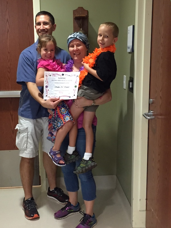 The Daniels family poses in front of the radiation treatment room’s victory wall, Sept. 26, 2016, at the San Antonio Military Medical Center with the hand prints of everyone who has gone through treatment in that room. The Daniels family’s hand prints are between them. (Courtesy photo)