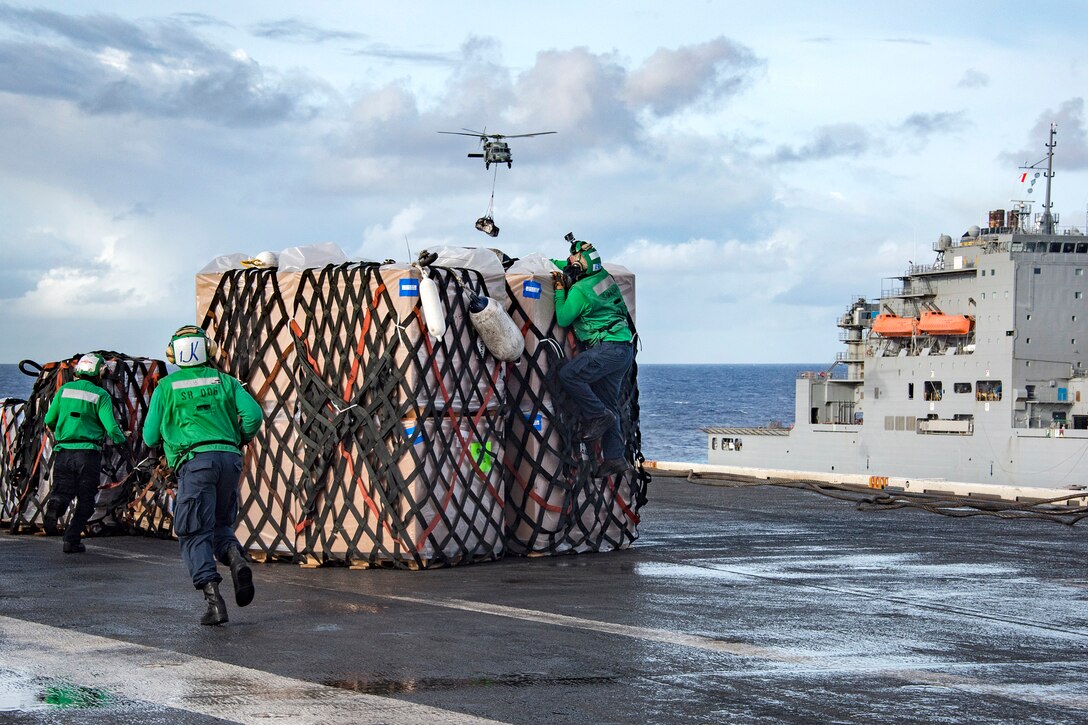Sailors hurry to remove cargo straps from pallets of supplies delivered by Navy MH-60S Sea Hawk helicopters to the aircraft carrier USS Carl Vinson during a vertical replenishment with the dry cargo and ammunition ship USNS Charles Drew in the Pacific Ocean, Feb. 3, 2017. Navy photo by Petty Officer 2nd Class Sean M. Castellano