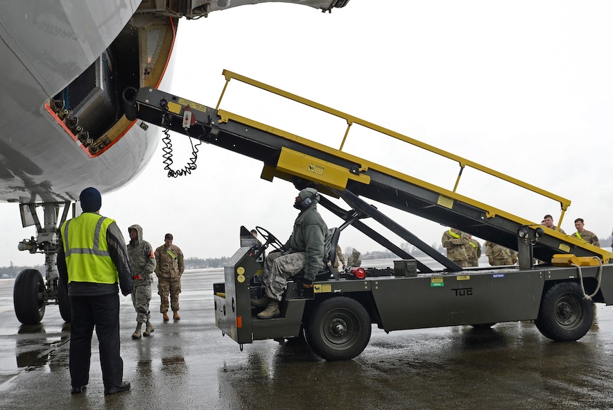 Staff Sgt. Christopher Craig (center), 62nd Aerial Port Squadron ramp services technician, pulls a ramp up to a transient aircraft Feb. 8, 2017 at Joint Base Lewis-McChord, Wash. Within the APS, the air terminal operations center manages the PAX terminal, ramps services section (loading and unloading of cargo), fleet services (cleaning the aircraft) and the special handling section (handling explosives). (U.S. Air Force photo/Senior Airman Divine Cox)