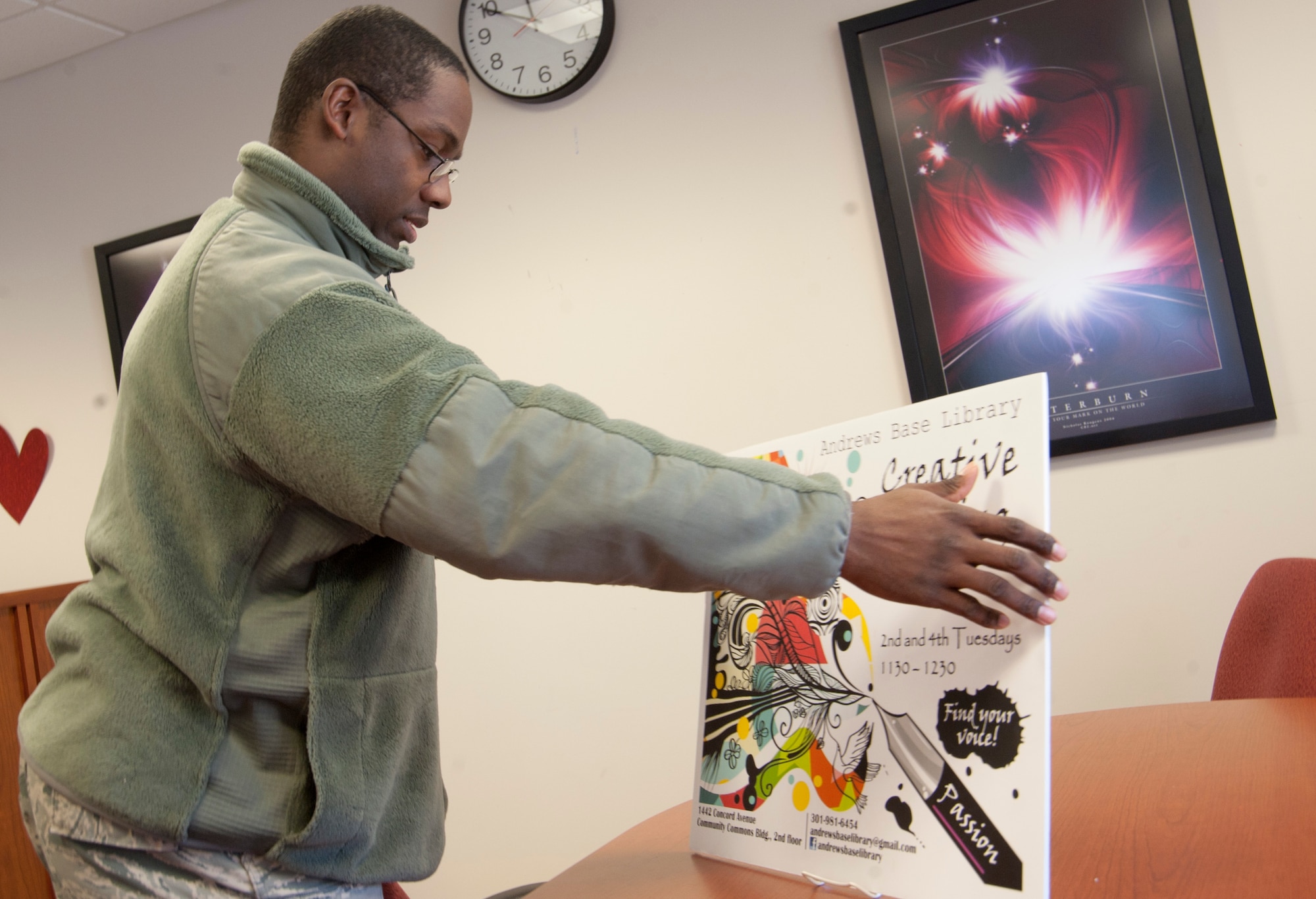 Tech. Sgt. Joseph Murray, 11th Force Support Squadron manpower analyst, sets a sign on a conference table that advertises his creative writing club meetings at the library on Joint Base Andrews, Md., Feb. 10, 2017. During each meeting, members come together to express themselves, in writing in a group setting as a means to explore their imaginations. (U.S. Air Force photo by Staff Sgt. Joe Yanik)