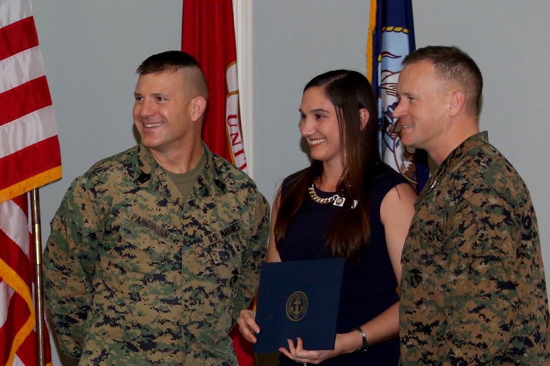 Stacy Mergen, center, was awarded for her efforts as a volunteer for the Navy-Marine Corps Relief Society during an annual banquet aboard Marine Corps Air Station Cherry Point, N.C., Feb. 9, 2017. Sgt. Maj. Benjamin Pangborn, left, and Col. Todd Ferry distributed awards based on hours and efforts donated to the society. Ferry is the commanding officer of MCAS Cherry Point and Pangborn is the air station sergeant major. (U.S. Marine Corps photo by Cpl. Jason Jimenez/ Released)