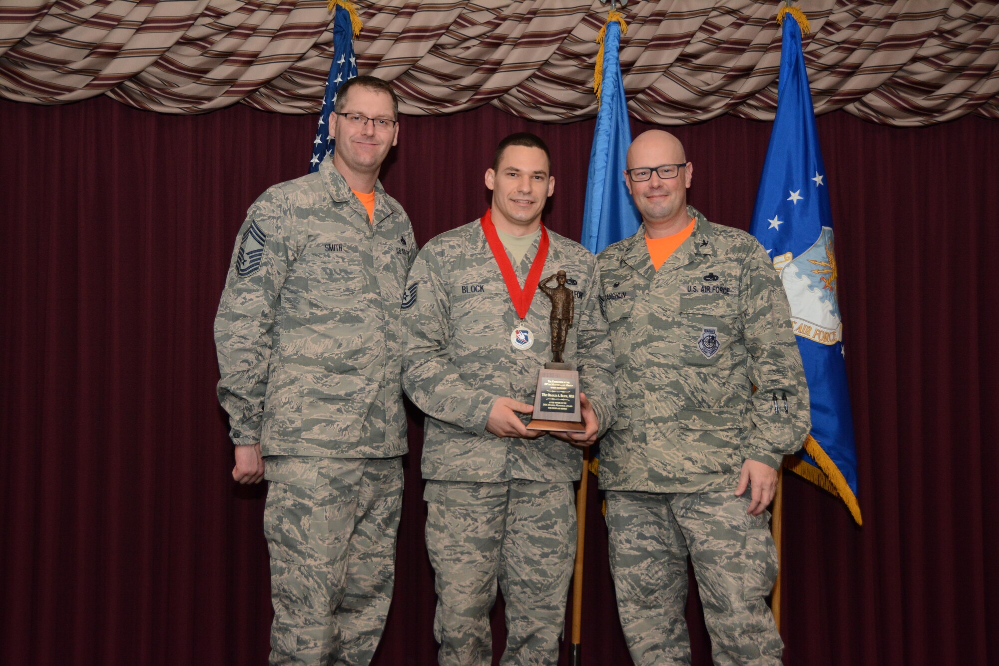 Tech. Sgt. Bradley Block (center) of the 507th Maintenance Squadron accepts the Tech. Sgt. Billy Hughes Memorial Award for best exemplifying the U.S. Air Force’s core values Feb. 4, 2017, in the Tinker Club Ballroom at Tinker Air Force Base, Okla. Chief Master Sgt. Mark Smith (left), 507th Maintenance Group superintendent and Col. Travis Caughlin (right), 507th Maintenance Group commander were on hand to present the award. (U.S. Air Force photo/Tech. Sgt. Lauren Gleason)
