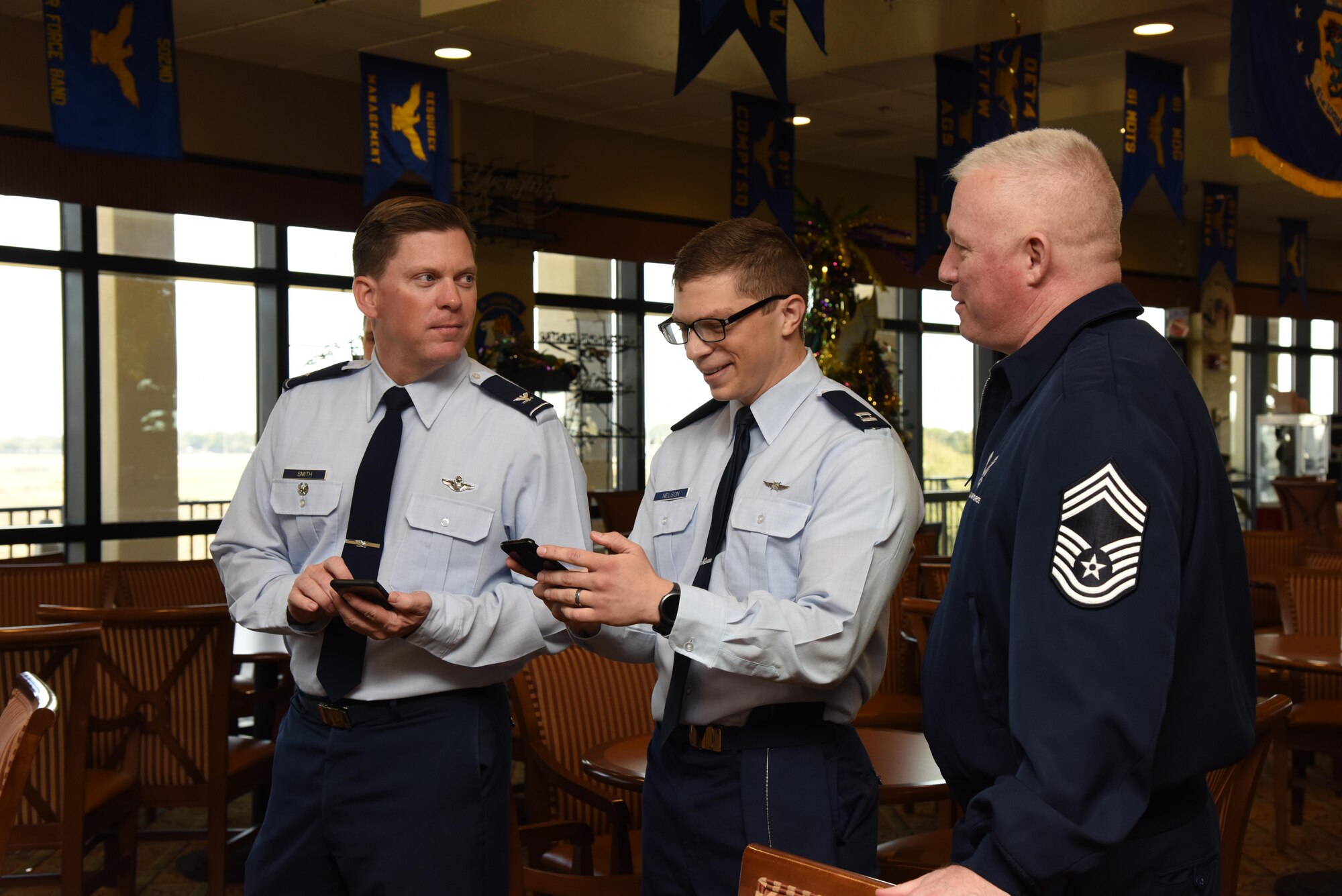 Col. C. Mike Smith, 81st Training Wing vice commander, Capt. Alexander Nelson, 81st Communications Squadron operations flight commander, and Chief Master Sgt. Derick Stepp, 81st Mission Support Group superintendent, use their cell phones to submit questions during a live multimedia broadcast system demonstration at the Bay Breeze Event Center Feb. 6, 2017, on Keesler Air Force Base, Miss. The conferencing system provides a way for someone at the BBEC to communicate with up to five locations on base via a livestream. (U.S. Air Force photo by Kemberly Groue)