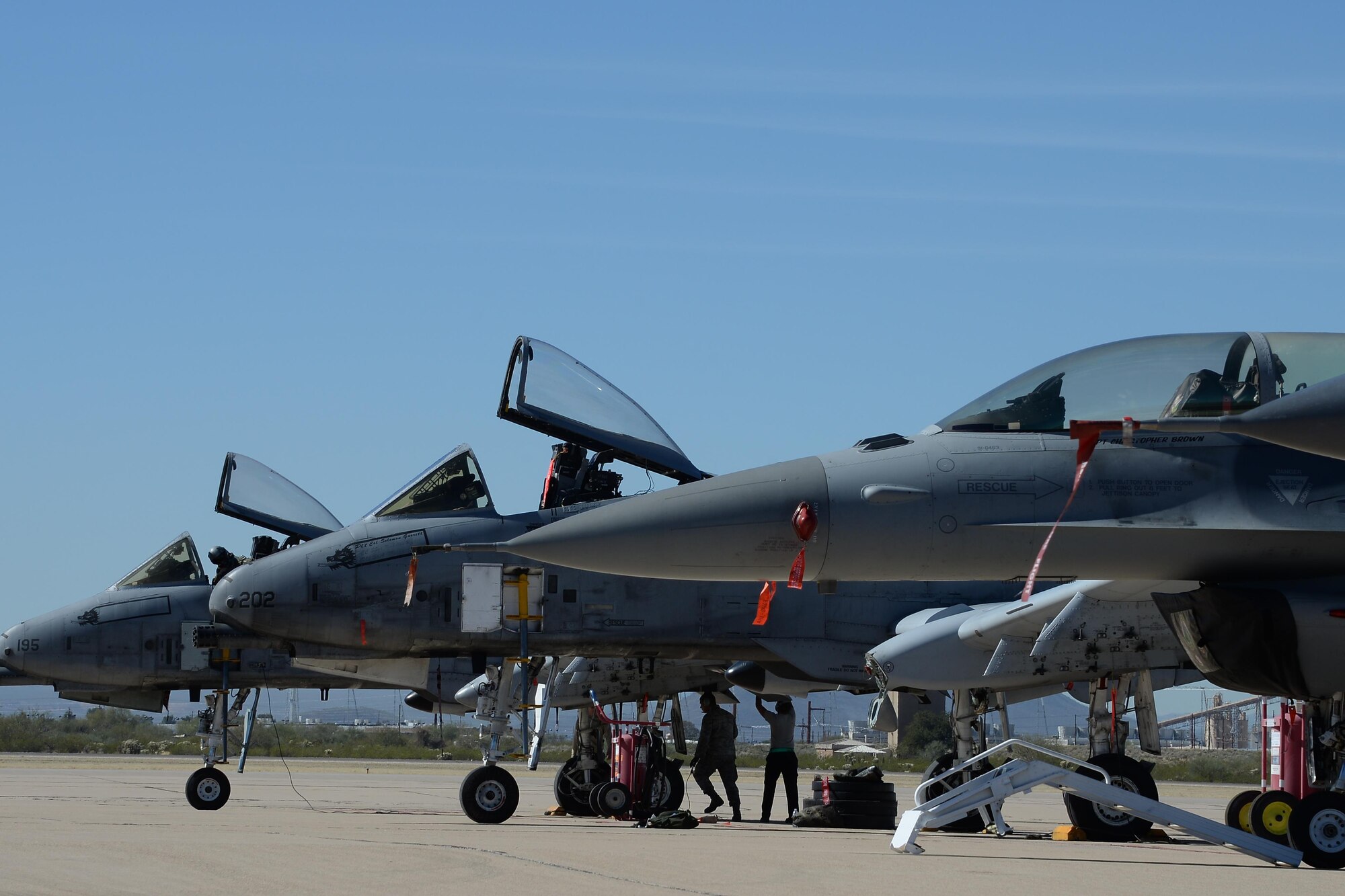 Two U.S. Air Force A-10C Thunderbolt IIs and an F-16 Fighting Falcon rest on the flightline during the 2017 Heritage Flight Training and Certification Course at Davis-Monthan Air Force Base, Ariz., Feb. 10, 2017. The modern aircraft that participated in this year's HFTCC were the F-35 Lightning II, the F-22 Raptor, F-16 Fighting Falcon and the A-10C Thunderbolt II. The historic aircraft included the P-51 and T-51 Mustangs, the P-40 Warhawk, the P-38 Lightning, the P-47 Thunderbolt, the T-33 Shooting Star and the F-86 Sabre. (U.S. Air Force photo by Senior Airman Ashley N. Steffen)