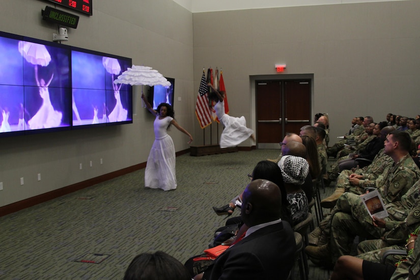 U.S. Army Central Soldiers watch members of the Kerende Dance Group perform while a clip of the Alvin Dance Company plays in the background during the USARCENT African American History observance, Feb. 8, at Shaw Air Force Base, S.C. 