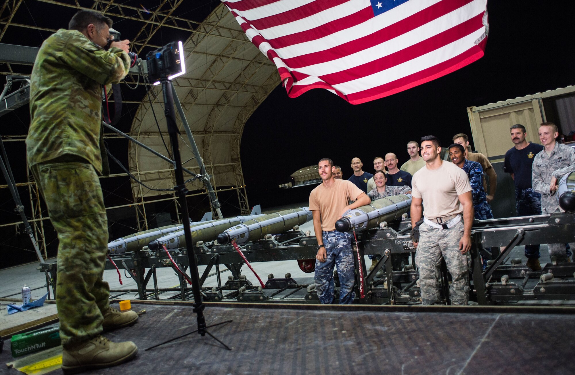 Royal Australian Air Force Cpl. David, an imagery specialist with the 77 Squadron, captures a group photo of RAAF and U.S. Air Force munition technicians at an undisclosed location in Southwest Asia, Feb. 9, 2016. During the shift Coalition partners assembled 8 Joint Direct Attack Munitions weighing a total of 4,000 pounds. (U.S. Air Force photo/Senior Airman Tyler Woodward)