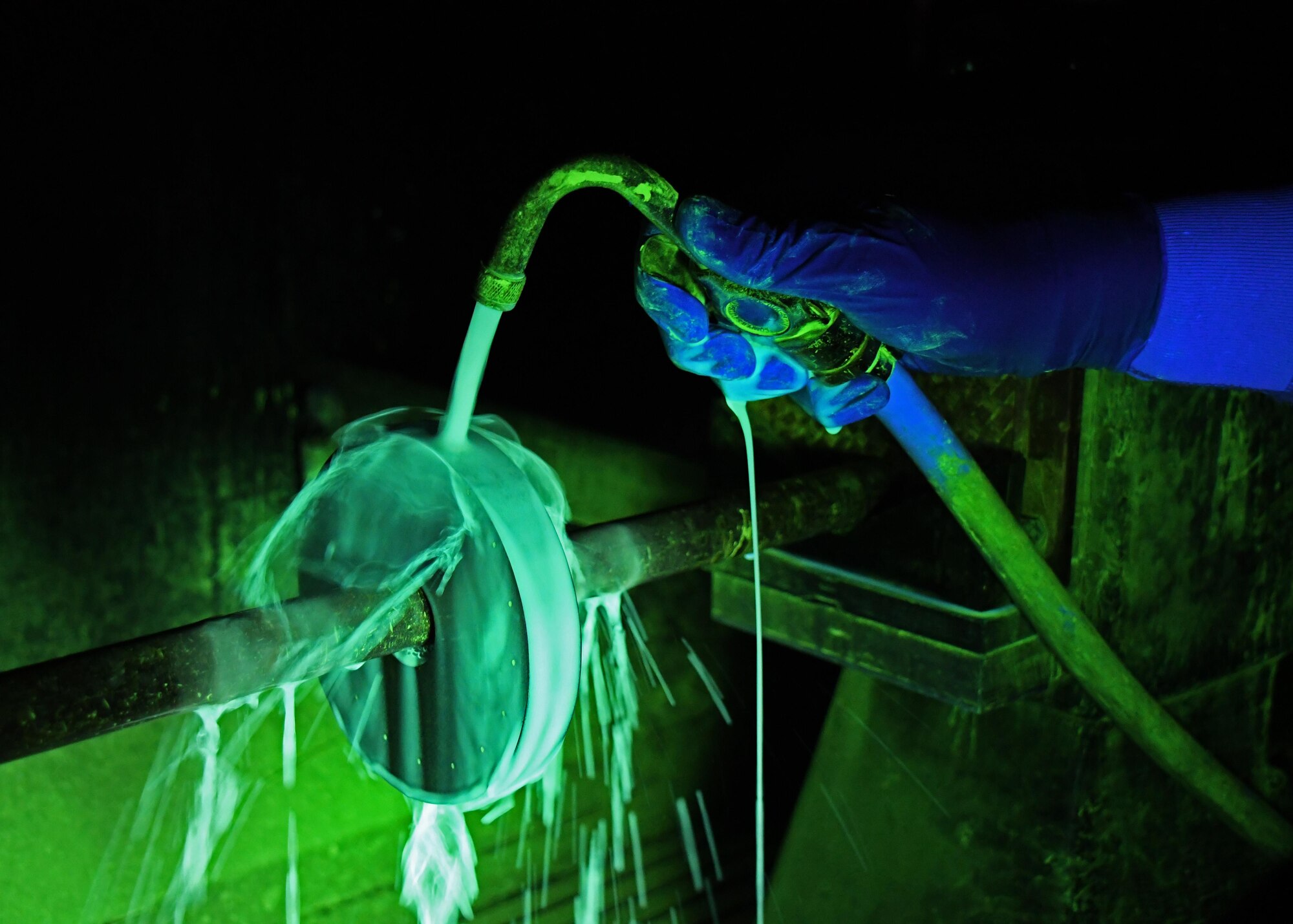 U.S. Air Force Airman 1st Class Austin Hall, a non-destructive inspection journeyman with the 379th Expeditionary Maintenance Squadron Fabrication Flight, rinses a piece of metal with an iron particle solution under a black light at Al Udeid Air Base, Qatar, Feb. 9, 2017. Hall was conducting a magnetic particle inspection to look for defects in the metal. (U.S. Air Force photo by Senior Airman Miles Wilson)