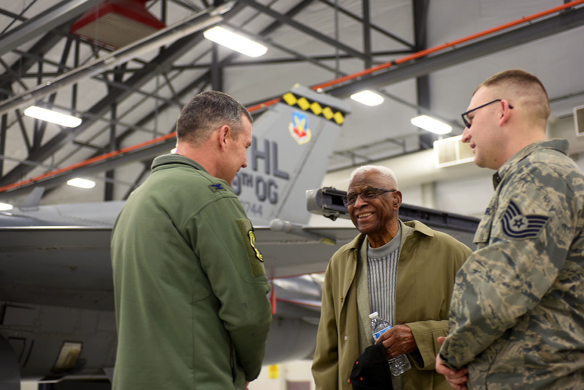 Retired Lt. Col. James H. Harvey III (center), member of the historic Tuskegee Airmen, talks to Col. David Smith, 419th Fighter Wing commander, and Tech. Sgt. David Batman, 419th Aircraft Maintenance Squadron, about the F-16 Fighting Falcon during a tour at Hill Air Force Base Feb. 11. (U.S. Air Force photo/Bryan Magaña)