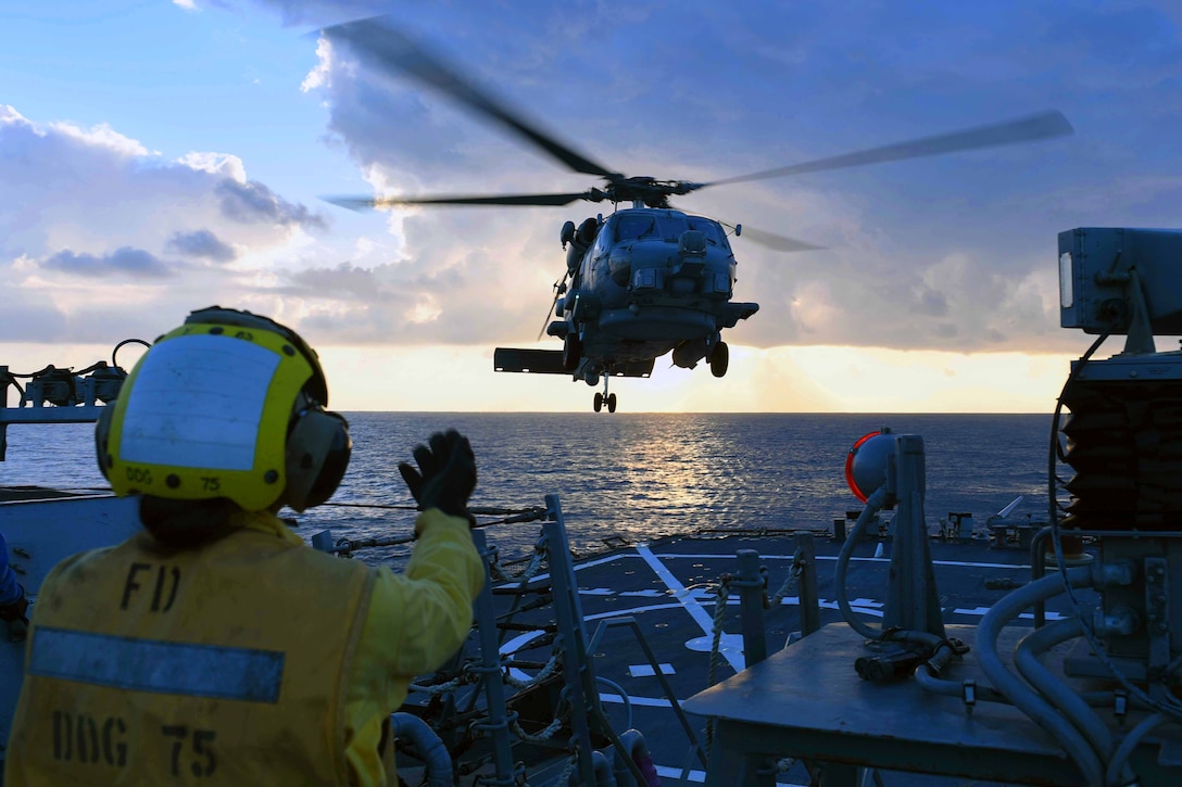 Seaman Dyamond P. Khammanivong signals to a helicopter hovering above the USS Donald Cook in the Mediterranean Sea, Feb. 8, 2017. Donald Cook, an Arleigh Burke-class guided-missile destroyer, is conducting naval operations in support of U.S. national security interests in Europe and Africa. Navy photo by Petty Officer 3rd Class Alyssa Weeks