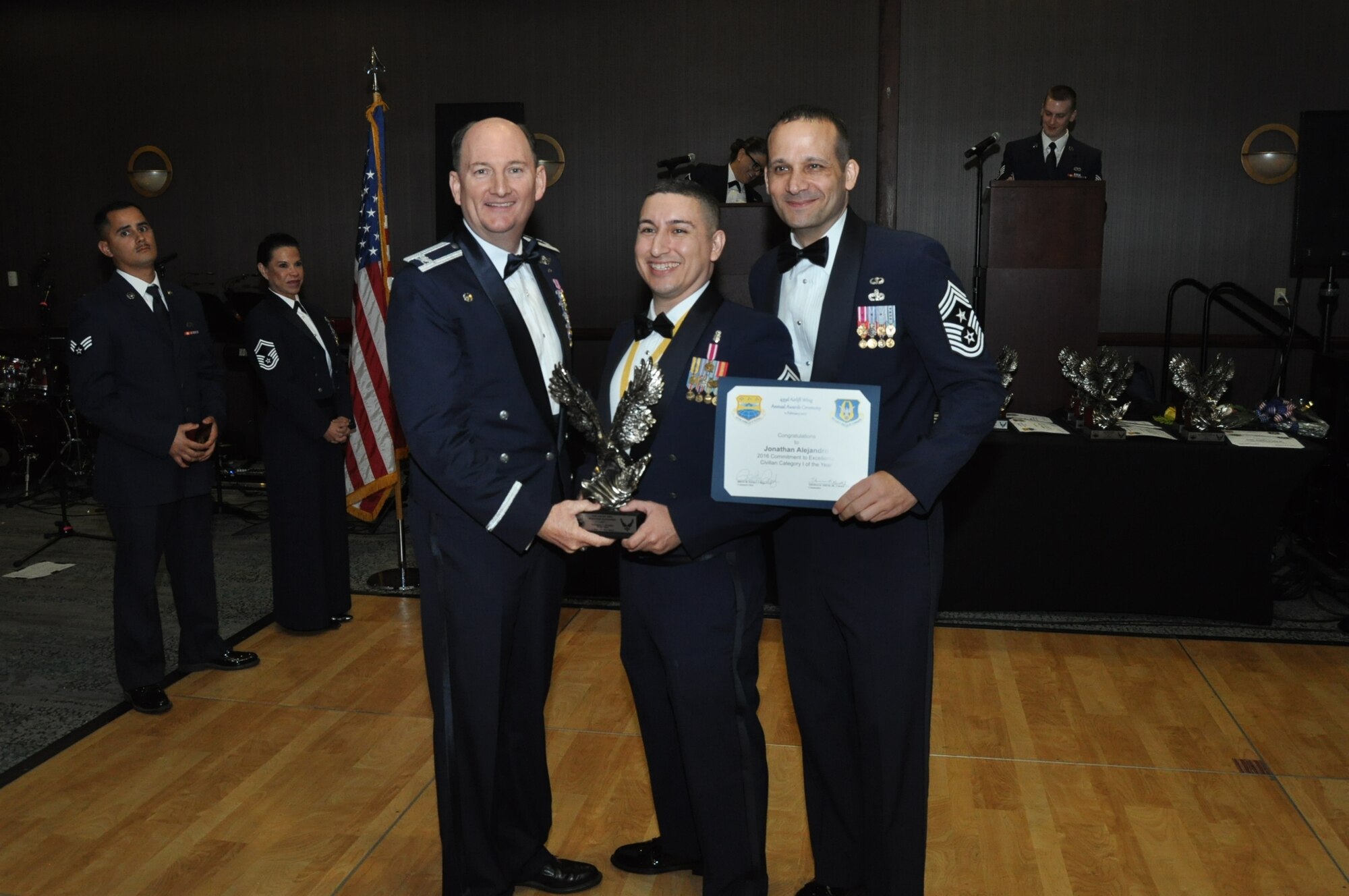 (Left) Col. Thomas K. Smith, Jr., 433rd Airlift Wing commander, and (Right) Chief Master Sgt. Brian Pinsky, 433rd AW command chief, present Jonathan Alejandro, 433rd Aerospace Medicine Squadron, the Category I annual award at the Alamo Wing’s Annual Award Banquet held at the Courtyard SeaWorld San Antonio Feb. 11, 2017. (U.S. Air Force photo/Senior Airman Bryan Swink)