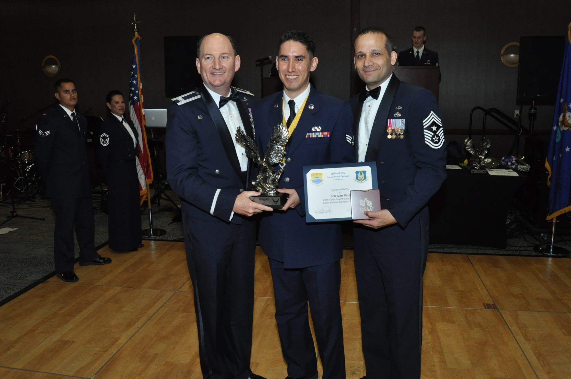 (Left) Col. Thomas K. Smith, 433rd Airlift Wing commander, and (Right) Chief Master Sgt. Brian Pinsky, 433rd AW command chief, present Senior Airman Ivan Vela, 433rd Maintenance Squadron, the Airman of the Year annual award at the Alamo Wing’s Annual Award Banquet held at the Courtyard SeaWorld San Antonio Feb. 11, 2017. (U.S. Air Force photo/Senior Airman Bryan Swink)