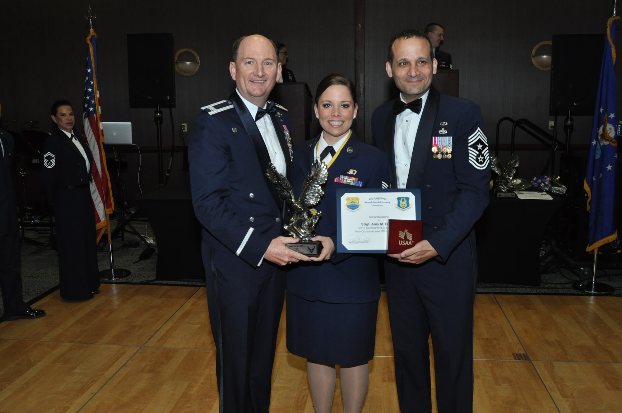 (Left) Col. T.K. Smith, 433rd Airlift Wing commander, and (Right) Chief Master Sgt. Brian Pinsky, 433rd AW command chief, present Staff Sgt. Amy M. Dennis, 433rd Airlift Control Flight, the Noncommissioned Officer of the Year annual award at the Alamo Wing’s Annual Award Banquet held at the Courtyard SeaWorld San Antonio Feb. 11, 2017. (U.S. Air Force photo/Senior Airman Bryan Swink)