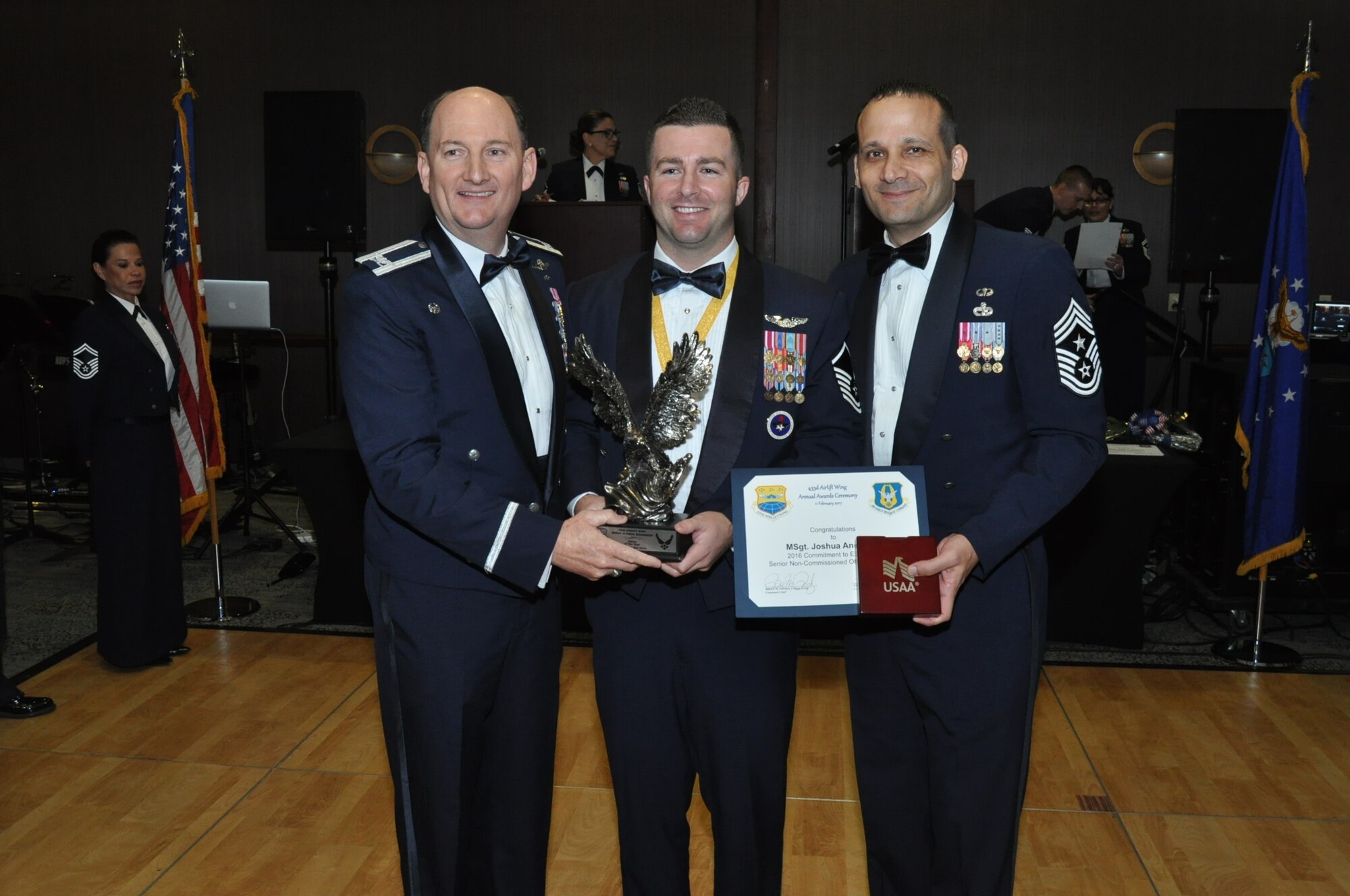 (Left) Col. Thomas K. Smith, Jr., 433rd Airlift Wing commander, and (Right) Chief Master Sgt. Brian Pinsky, 433rd AW command chief, present Senior Master Sgt. Joshua Anderson, 733rd Training Squadron, the Senior NCO of the Year annual award at the Alamo Wing’s Annual Award Banquet held at the Courtyard SeaWorld San Antonio Feb. 11, 2017. (U.S. Air Force photo/Senior Airman Bryan Swink)