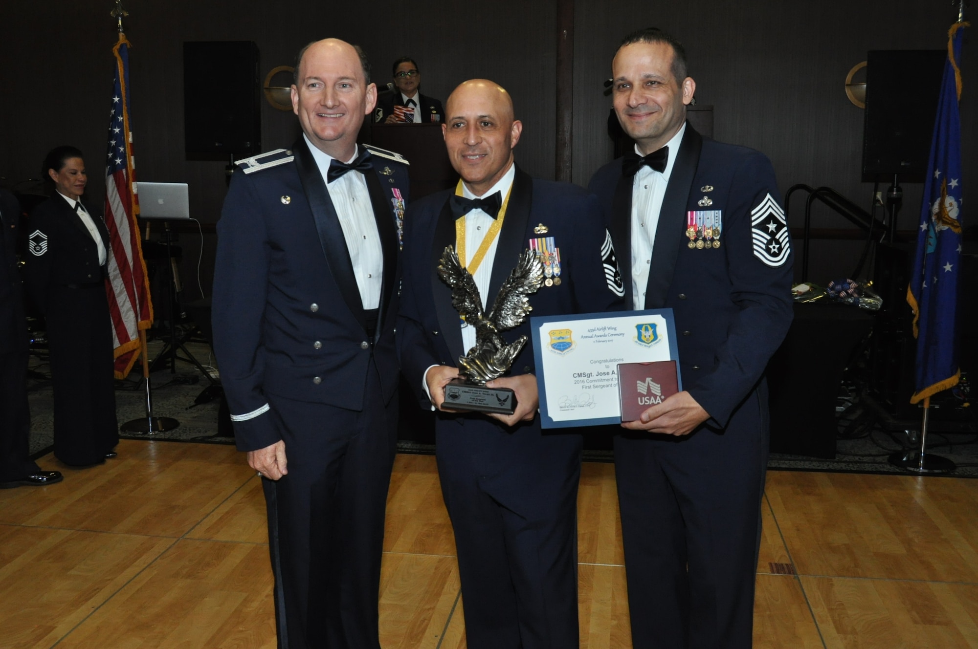 (Left) Col. Thomas K. Smith, Jr.,  433rd Airlift Wing commander, and (Right) Chief Master Sgt. Brian Pinsky, 433rd AW command chief, present Chief Master Sgt. Jose A. Velez, JR., 433rd Maintenance Squadron, the First Sergeant of the Year annual award at the Alamo Wing’s Annual Award Banquet held at the Courtyard SeaWorld San Antonio Feb. 11, 2017. (U.S. Air Force photo/Senior Airman Bryan Swink)