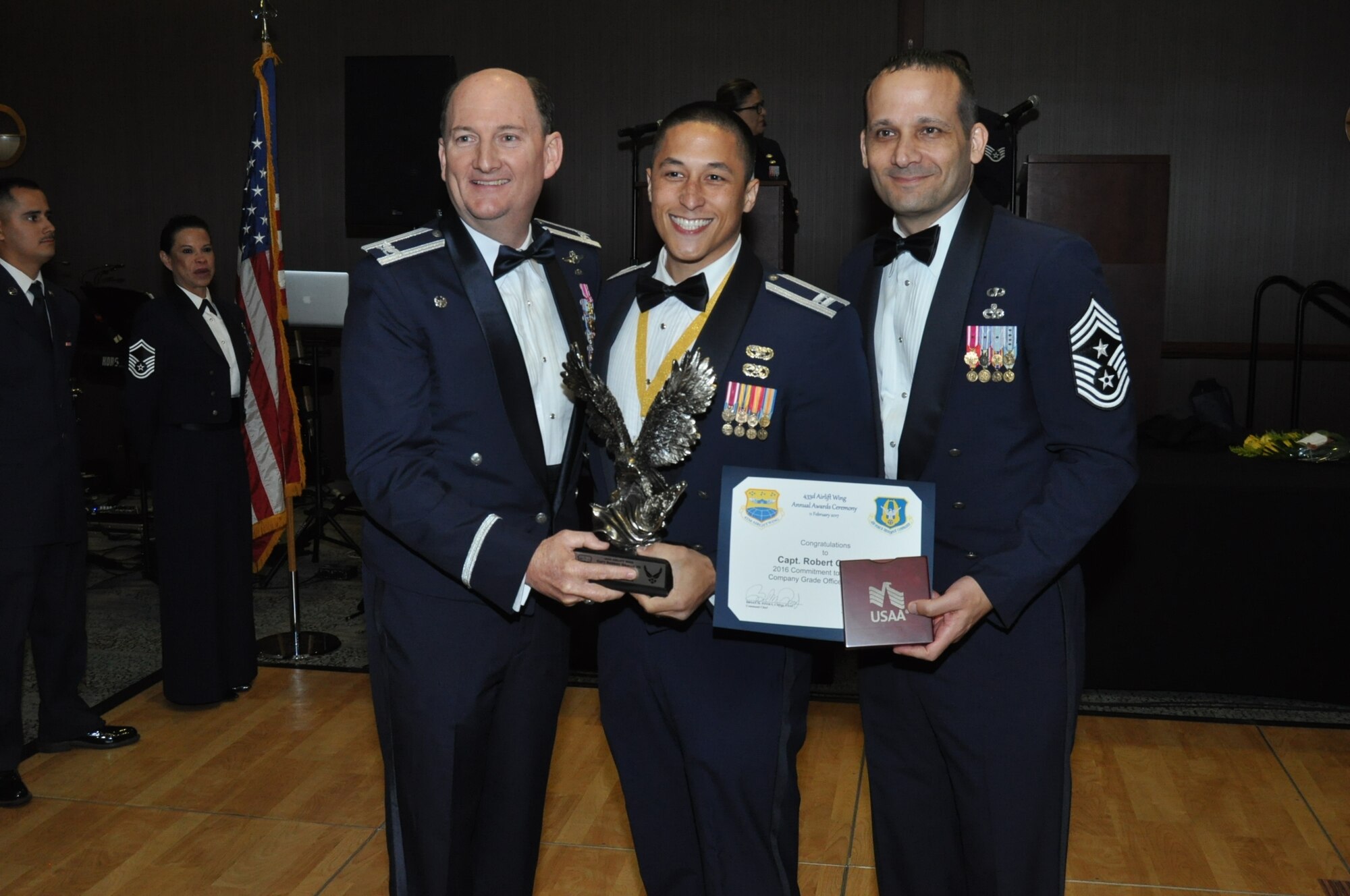 (Left) Col. Thomas K. Smith, Jr., 433rd Airlift Wing commander, and (Right) Chief Master Sgt. Brian Pinsky, 433rd AW command chief, present Capt. Robert Orallo III, 26th Aerial Port Squadron, the Company Grade Officer of the Year annual award winner at the Alamo Wing’s Annual Award Banquet held at the Courtyard SeaWorld San Antonio Feb. 11, 2017. (U.S. Air Force photo/Senior Airman Bryan Swink)