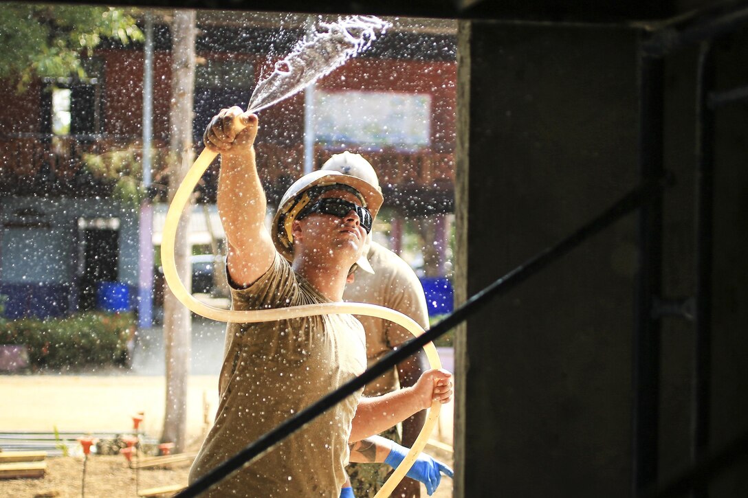 Navy Petty Officer 2nd Class Tyler Dowling sprays down a wall during the construction of a classroom during exercise Cobra Gold at Ban Nong Muang School, Rayong Province, Thailand, Feb. 10, 2017. Dowling is a construction equipment operator assigned to Naval Mobile Construction Battalion 5. Marine Corps photo by Cpl. Wesley Timm 