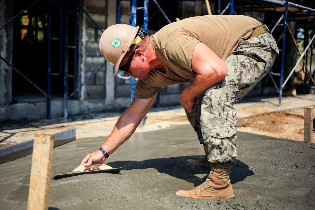 Navy Petty Officer 1st Class Kevin Meyers trowels cement during the construction of a classroom during exercise Cobra Gold at Ban Nong Muang School, Rayong Province, Thailand, Feb. 10, 2017. Meyers is a builder assigned to Naval Mobile Construction Battalion 5. Marine Corps photo by Cpl. Wesley Timm 