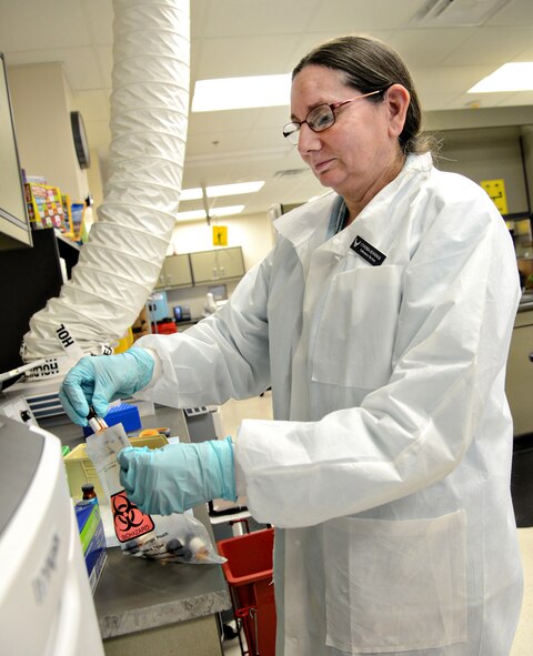 Cynthia Jennings, a medical technologist with the 72nd Medical Support Squadron, disposes of samples that have already been tested with the laboratory’s chemistry analyzer. (Air Force photo by Kelly White)