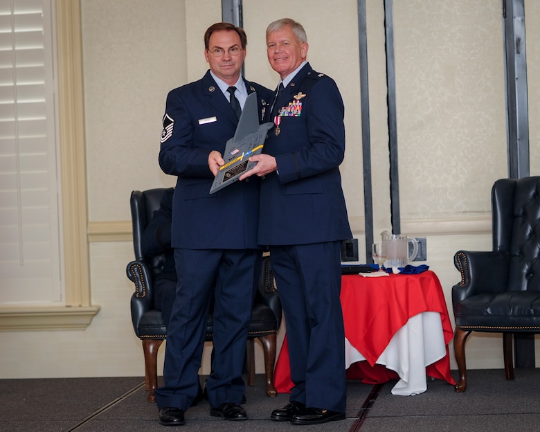(From left) Master Sgt. Eugene Rorie, 317th Airlift Squadron loadmaster, , presents retiring, Lt.. Col. Rick Davis, 317th AS, with a gift of a Charleston T-tail during his retirement ceremony at Joint Base Charleston, S.C Feb. 12. (U.S. Air Force photo by Senior Airman Tom Brading)