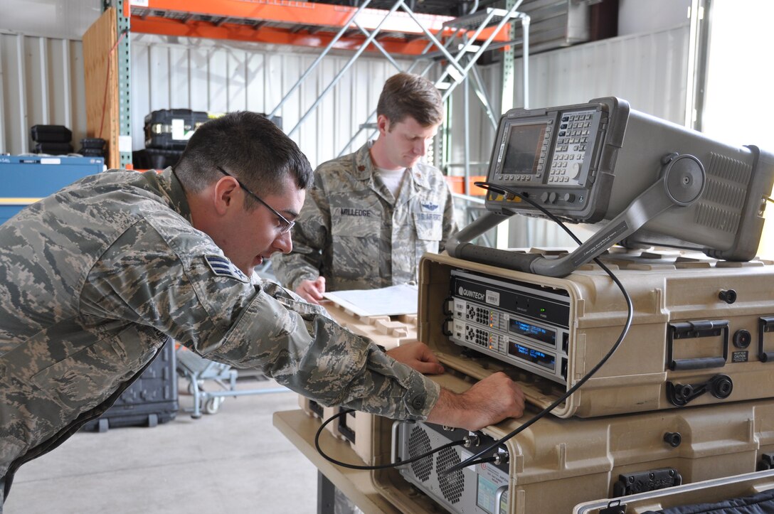 (Front to rear) Senior Airman Richard Sorensen and Maj. Aaron Milledge, GPS denial operators, set up high-power GPS electromagnetic interference training equipment. The hardware suite consists of a spectrum analyzer that verifies that the antenna and power are operating within safe parameters, a modem that builds a signal, and a high-powered amplifier. (U.S. Air Force photo/Maj. Jessica D'Ambrosio)