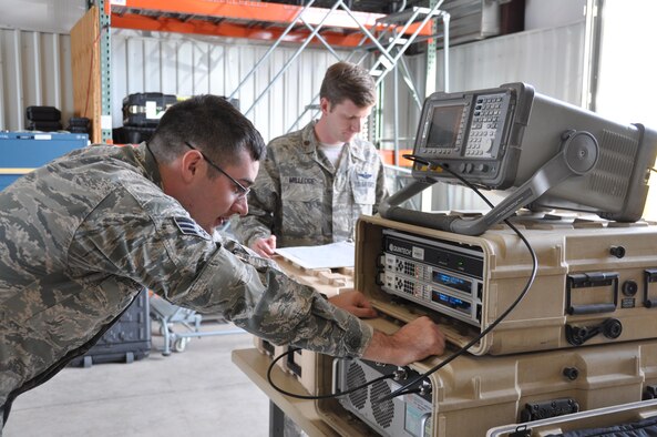 (Front to rear) Senior Airman Richard Sorensen and Maj. Aaron Milledge, GPS denial operators, set up high-power GPS electromagnetic interference training equipment. The hardware suite consists of a spectrum analyzer that verifies that the antenna and power are operating within safe parameters, a modem that builds a signal, and a high-powered amplifier. (U.S. Air Force photo/Maj. Jessica D'Ambrosio)