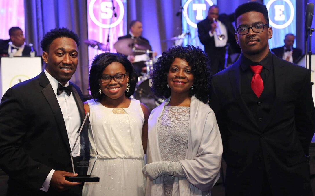 WASHINGTON (Feb. 11, 2017) - Dwayne Nelson, Naval Surface Warfare Center Dahlgren Division engineer, holds his Black Engineer of the Year (BEYA) Award after being honored for his community service accomplishments at the 31st annual BEYA gala. Standing left to right are Dwayne; his sister, Olivia; mother, Linda; and brother, Rudy. "To my family, friends, Alpha Phi Alpha fraternity brothers, and co-workers, a simple thank you is definitely not enough to tell you how much I wholeheartedly appreciate everything you’ve done for me," said Nelson. "I never would have made it here without you. Your support has been amazing!" (U.S. Navy photo by Rear. Adm. Tom Druggan/Released)