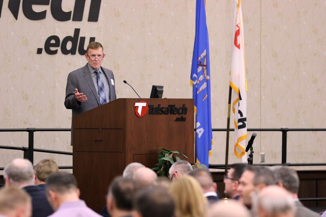 Gene Snyman, Tulsa District Small Business Office deputy, speaks at the 7th Annual Meet the Corps Day at Tulsa Technical Center in Owasso, Oklahoma.  Meet the Corps Day brought businesses and Tulsa District personnel together to talk about future contracts and exchange information.