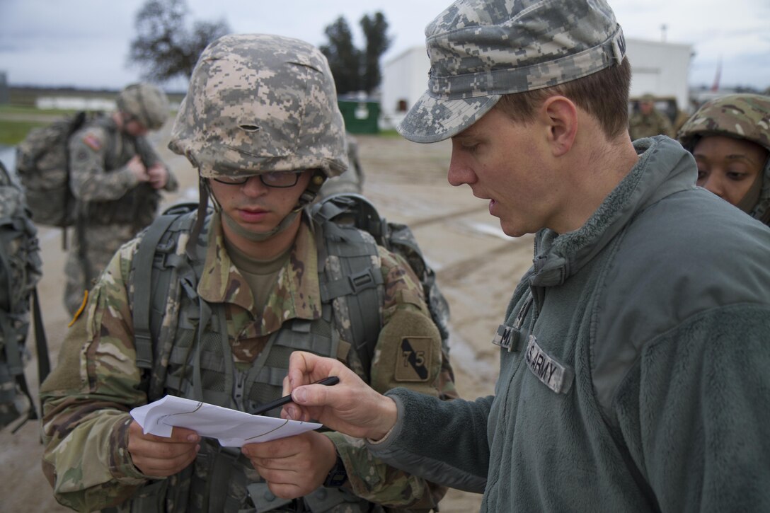 U.S. Army soldier Pfc. Juan Millan (left) is shown the designated course by Sfc. Kaleb Matlack (right) before the ruck march during the Best Warrior Competition Fort Hunter Liggett, Calif. on February 8, 2016. The course was 6 miles long and the rucks weighed around 35 pounds. (