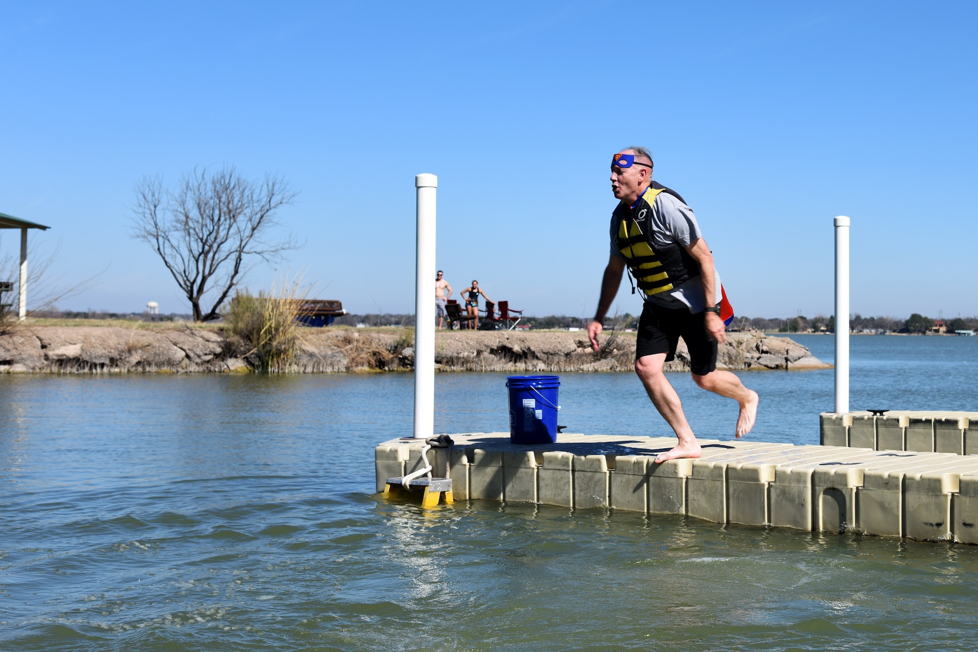U.S. Air Force Col. Michael Downs, 17th Training Wing Commander, jumps into Lake Nasworthy during the Polar Bear Party at the Goodfellow Air Force Base Recreation Camp in San Angelo, Texas, Feb. 11, 2017. Before taking the plunge, Downs also participated in the 5K run for the same event. (U.S. Air Force photo by Staff Sgt. Joshua Edwards/Released)