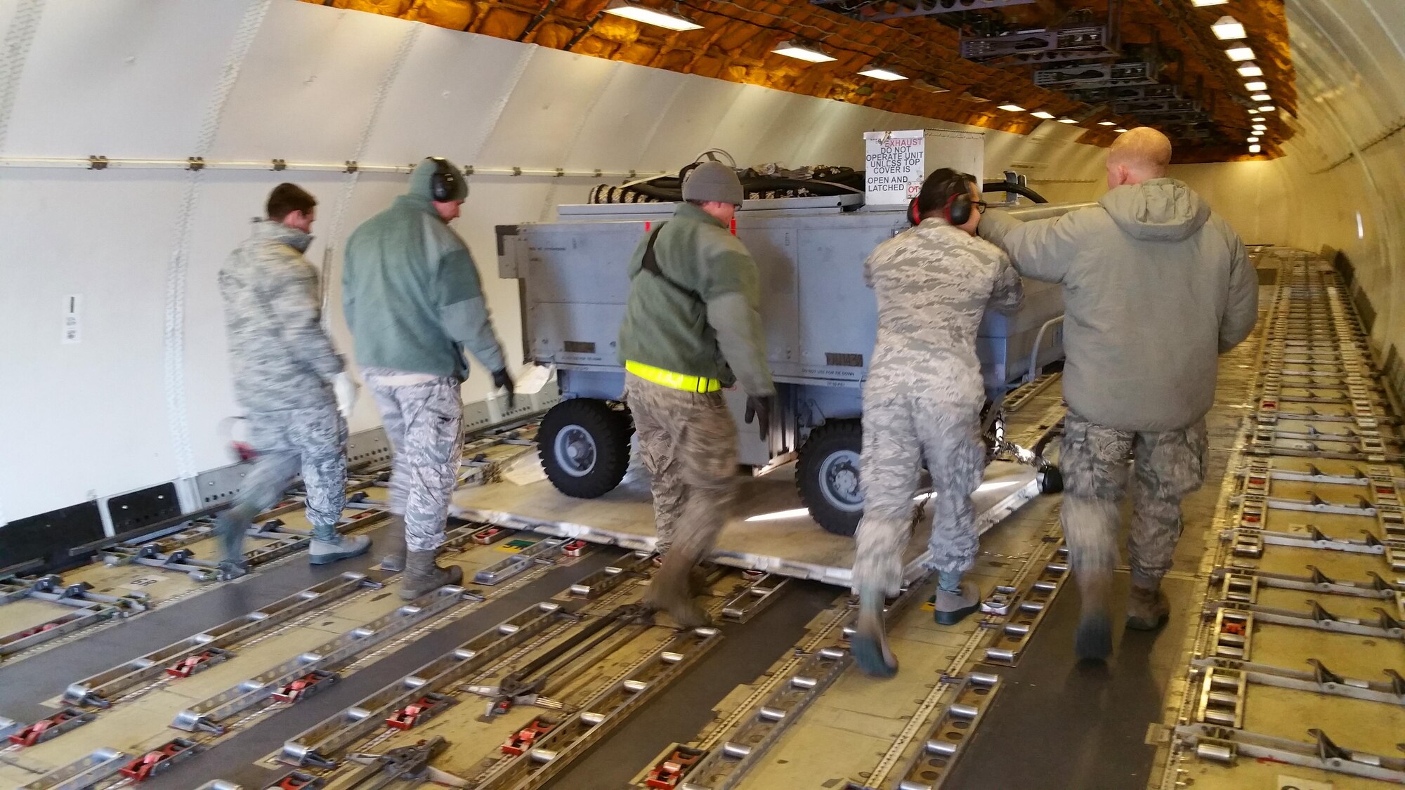 A picture of U.S. Air National Guard unit members from the 177th Fighter Wing helping to position pallets of maintenance and support equipment onto a Federal Express MD-11 aircraft.