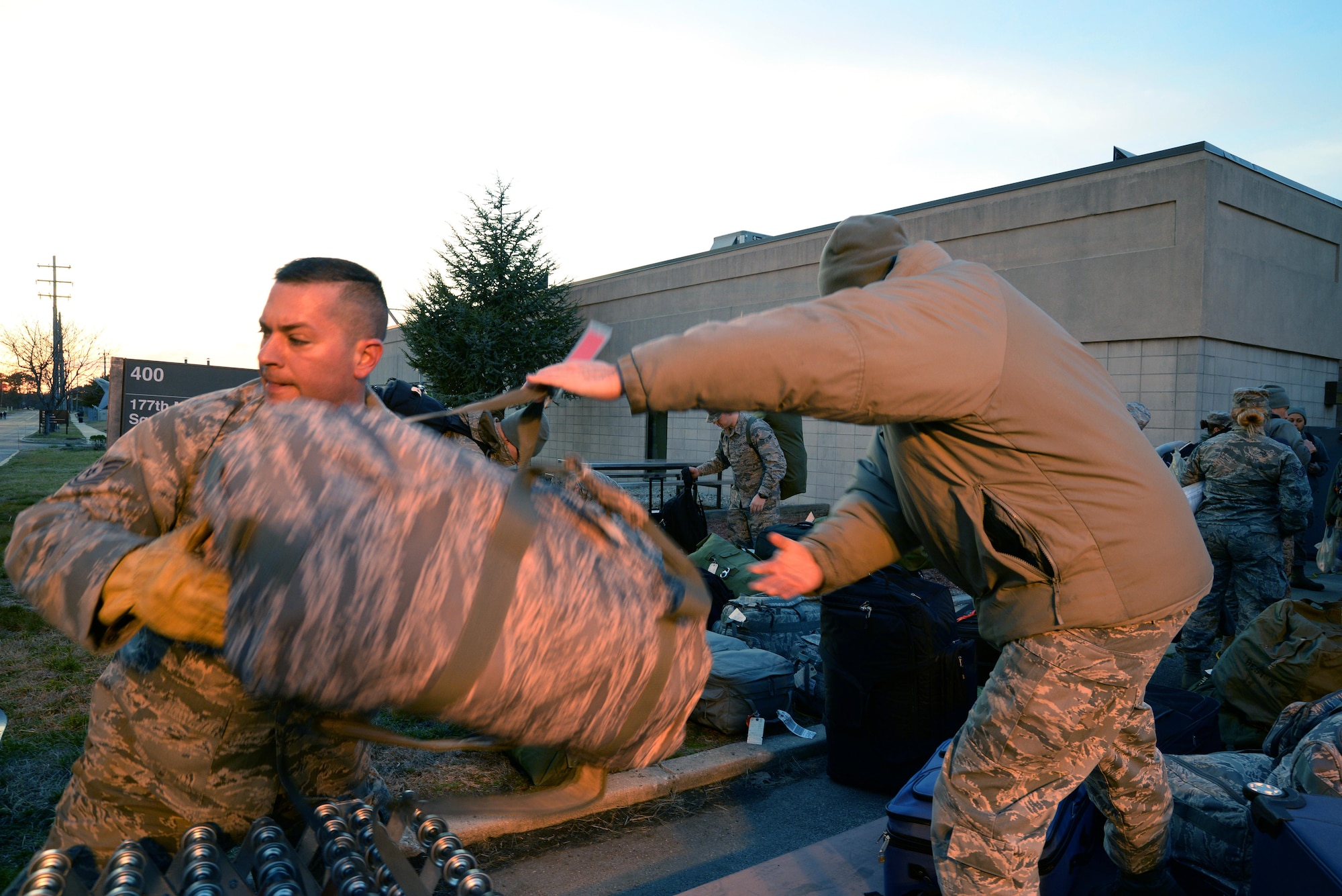 A picture of Airmen from the New Jersey Air National Guard's 177th Fighter Wing loading luggage onto a rolling conveyor table.