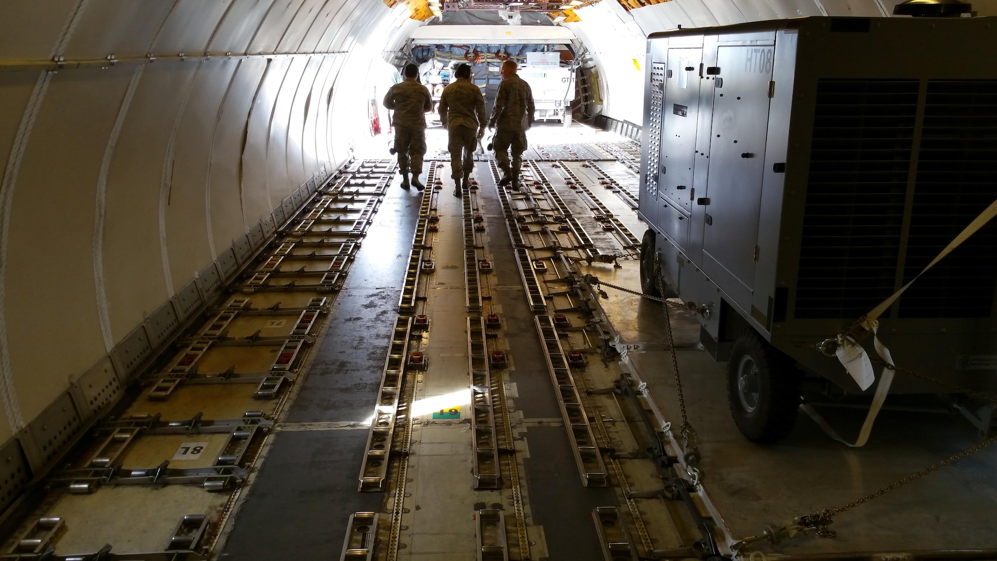 A picture of U.S. Air National Guard unit members from the 177th Fighter Wing Legal Office, Communications Flight, and Civil Engineer Squadron returning to the front of a Federal Express MD-11 aircraft.