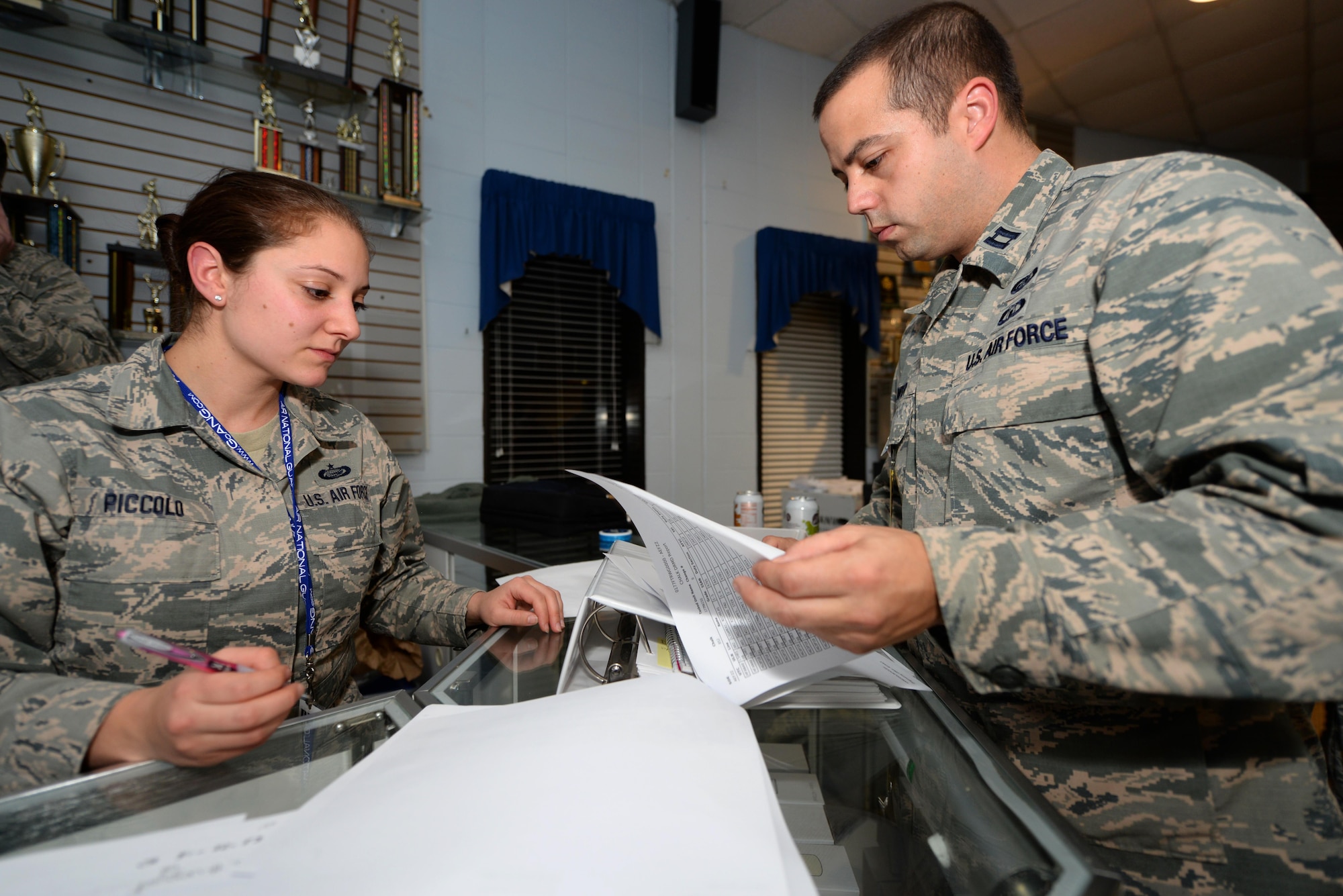 A picture of U.S. Air Force Capt. John Dwyer, 177th Fighter Wing Force Support Squadron Commander, and Tech. Sgt. Nicole Piccolo, with the Personnel Deployment Function at the Atlantic City Air National Guard Base, N.J., reviewing the passenger manifest of New Jersey Air National Guard unit members deploying to Osan Air Base, Republic of Korea.