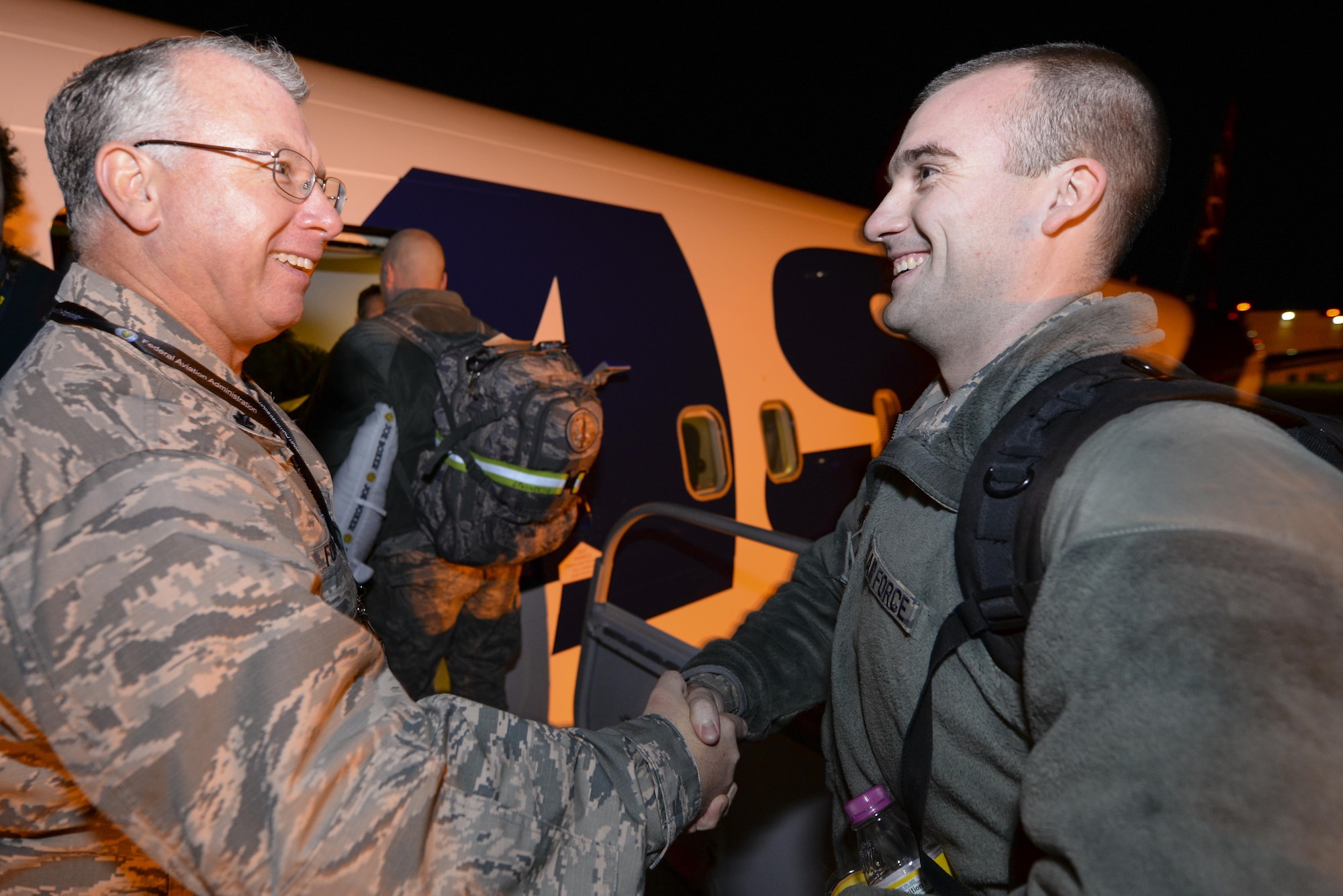 A picture of U.S. Air Force Lt. Col. John Fogarty, left, Logistics Readiness Squadron Commander with the New Jersey Air National Guard's 177th Fighter Wing, shaking the hands of Airmen who are boarding a commercial aircraft.
