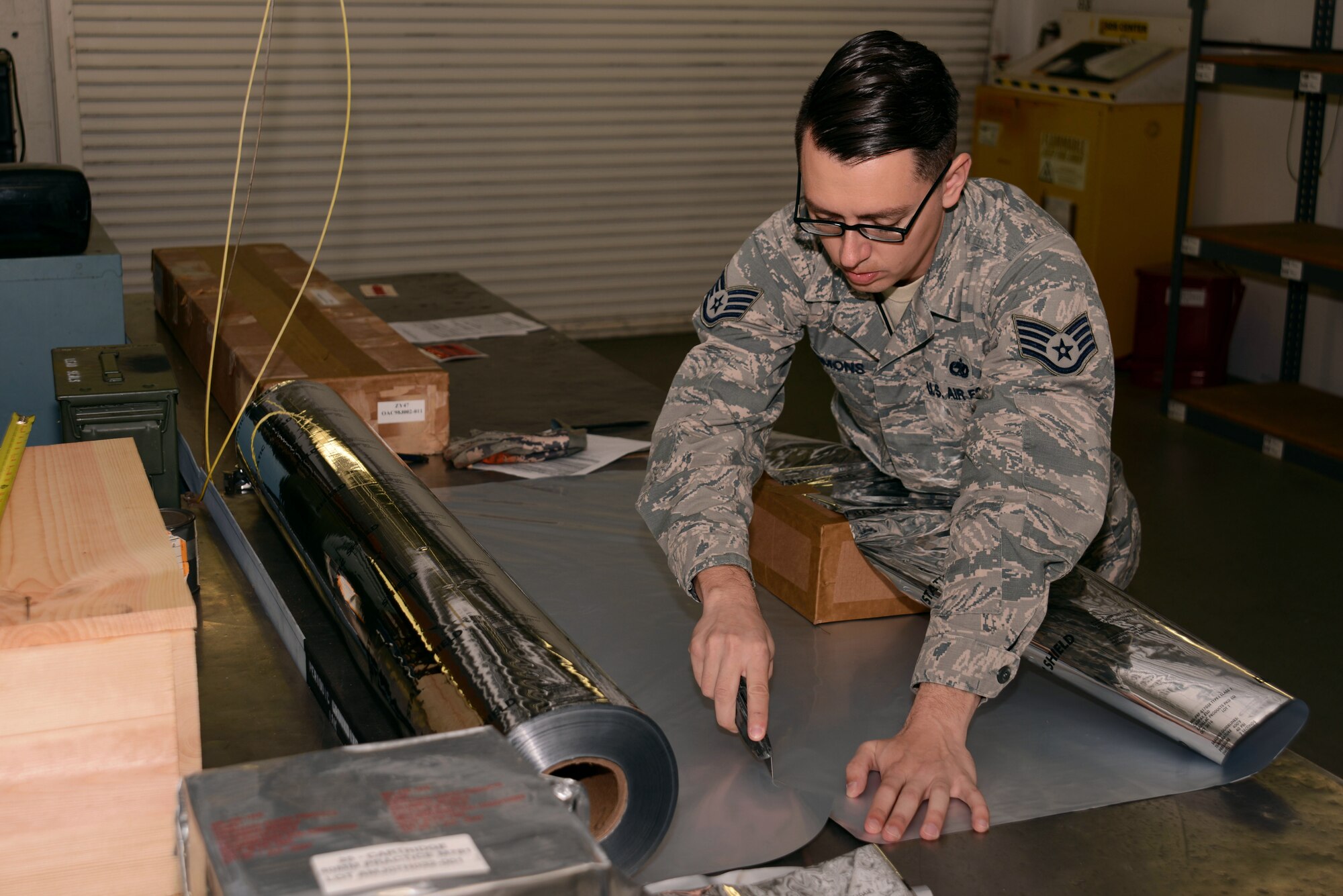 U.S. Air Force Staff Sgt. Ralph Simons, 20th Equipment Maintenance Squadron munitions inspector, cuts a vacuum seal barrier bag to properly fit a packed box of 40 mm grenades at Shaw Air Force Base, S.C., Feb. 6, 2017. The barrier bag acts as a static shield, preventing static that could detonate the munition. (U.S. Air Force photo by Airman 1st Class Kathryn R.C. Reaves)