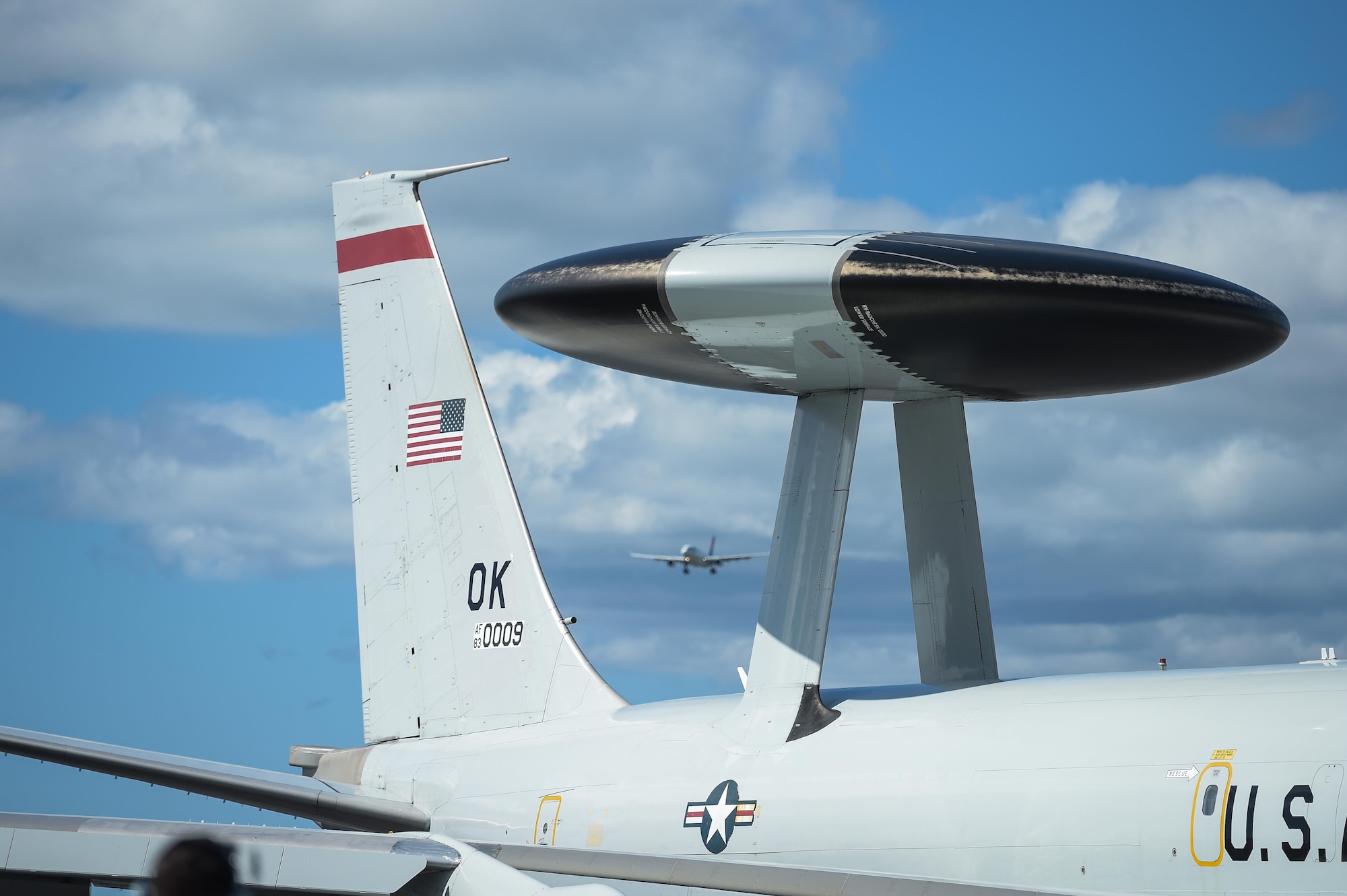 An E-3 Sentry Airborne Warning and Control System aircraft taxis into place Jan. 25 after returning from a mission at Joint Base Pearl Harbor-Hickam, Hawaii, while a passenger airplane prepares to land in the background. Reservists from the 513th Air Control Group deployed to the Hawaiian Islands to provide command and control for Sentry Aloha 17-01, a primarily Reserve and Air National Guard exercise that involves more than 40 aircraft and 1,000 personnel. (U.S. Air Force photo by 2nd Lt. Caleb Wanzer)