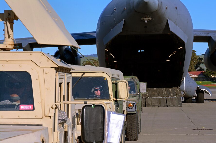 Army Reserve Spec. James Williams, 801st Engineer Company horizontal engineer, awaits the go ahead for Humvees to be backed into a C-17 Globemaster III prior to its take off from Travis Air Force Base, Calif., for Patriot Wyvern on Feb. 11, 2017. Patriot Wyvern is a hands-on, bi-annual event conducted by the 349th Air Mobility Wing designed to hone combat skills and improve organizational interoperability. (U.S. Air Force photo/Staff Sgt. Daniel Phelps)