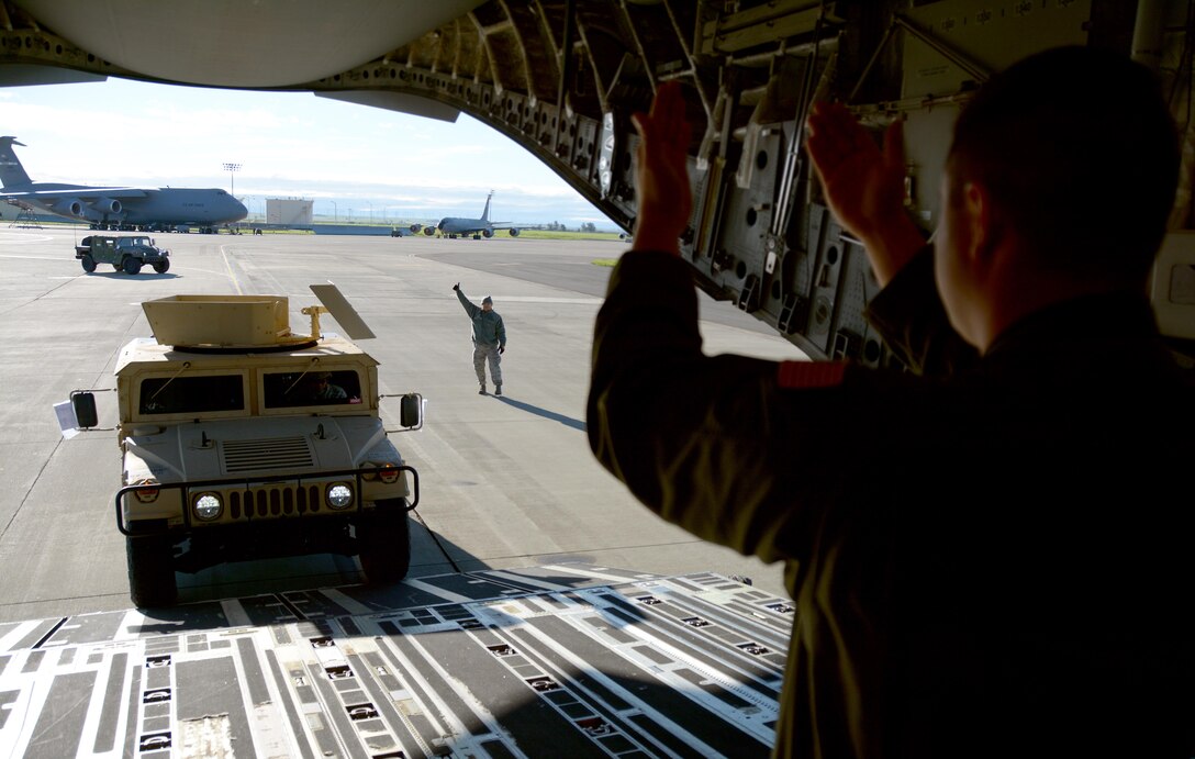 Air Force Staff Sgt. Devon Smith, 301st Airlift Squadron loadmaster, guides a Soldier from the 801st Engineer Company in a Humvee onto a C-17 Globemaster III prior to its take off from Travis Air Force Base, Calif., for Patriot Wyvern on Feb. 11, 2017. Patriot Wyvern is a hands-on, bi-annual event conducted by the 349th Air Mobility Wing designed to hone combat skills and improve organizational interoperability. (U.S. Air Force photo/Staff Sgt. Daniel Phelps)