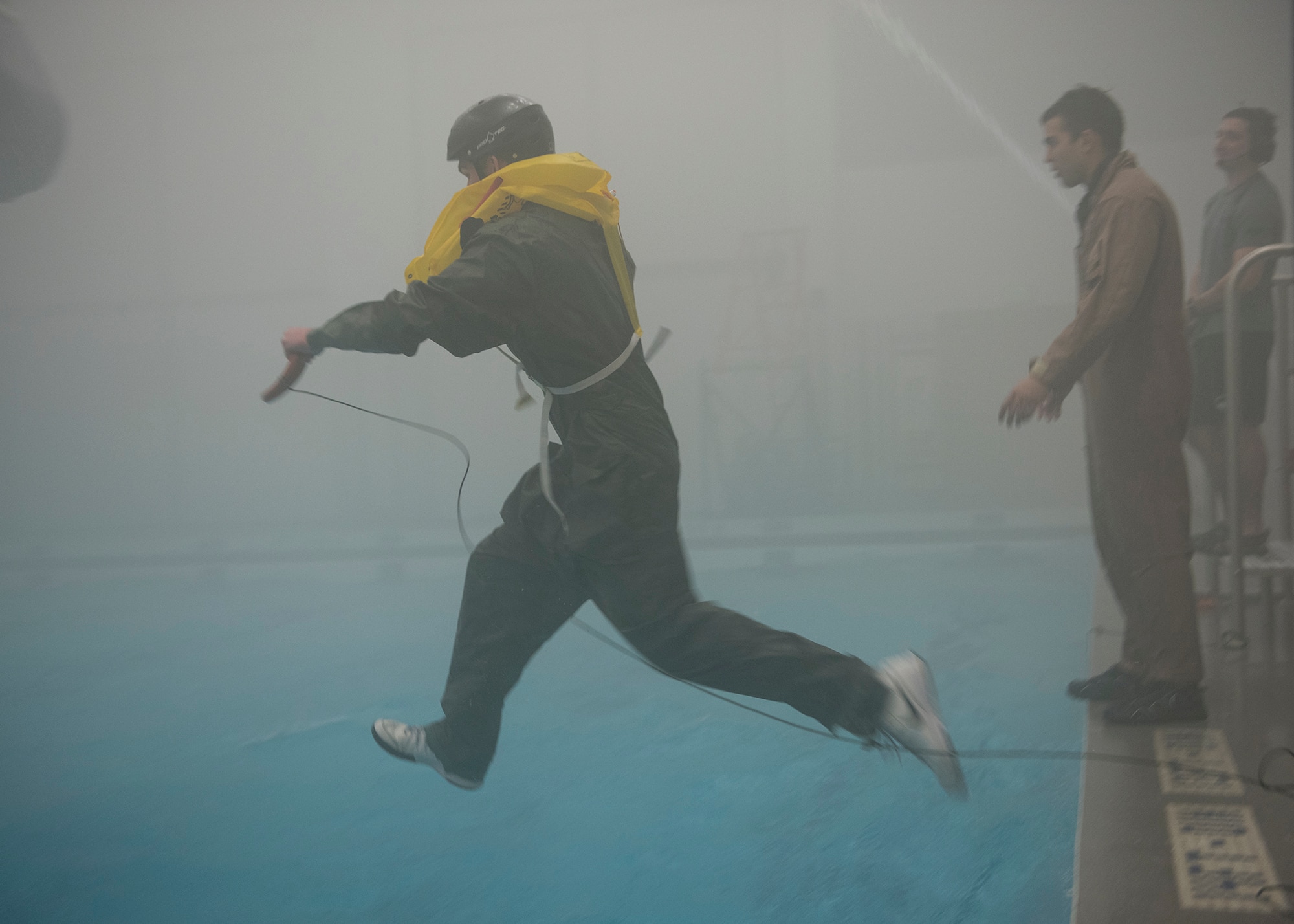 A Survival School student leaps toward a simulated rescue helicopter for rescue during a training session Feb. 10, 2017, at Fairchild Air Force Base, Wash. The fitness center pool was not originally designed with water survival training in mind, but was adapted to service training needs. (U.S. Air Force photo/ Airman 1st Class Ryan Lackey)