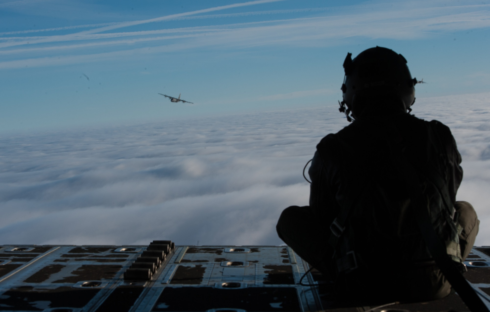 Airman 1st Class Quinn Harris, 37th Airlift Squadron loadmaster, peers over the skies at another C-130J Super Hercules flying over a blanket of clouds in Germany Feb. 10, 2017. During the Korean War, the squadron flew airborne assaults at Sukchon and Munsan-ni and aerial transportation between Japan and Korea. (U.S. Air Force photo by Senior Airman Lane T. Plummer)