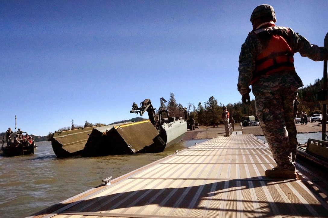 Army National Guard soldiers observe members of their unit unloading of a segment of an improved ribbon bridge at Whiskeytown Lake, near Redding, Calif., Feb. 11, 2017. Army National Guard photo by Spc. Amy E. Carle 