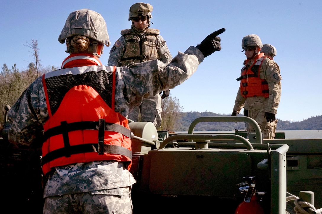 Army National Guard Sgt. Ellie Ogsbury, foreground, directs construction of a float bridge during training at Whiskeytown Lake, near Redding, Calif., Feb. 11, 2017. Ogsbury is a soldier assigned to the California Army National Guard’s 132nd Multi-Role Bridge Company. Army National Guard photo by Spc. Amy E. Carle 