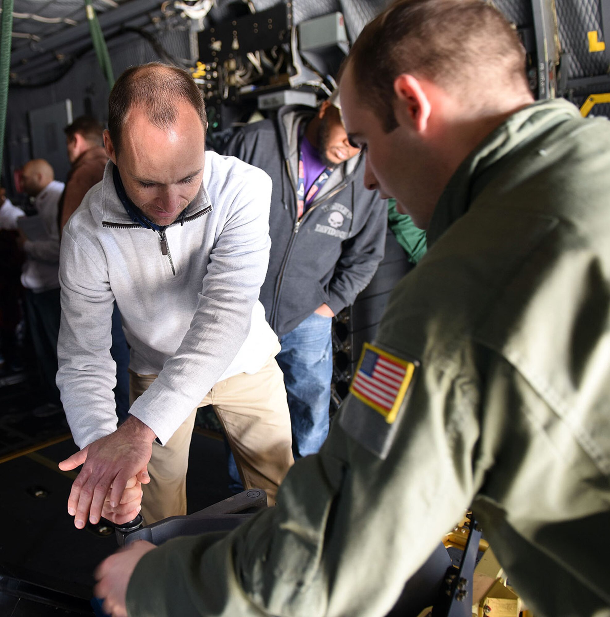 Todd Sanders, 568th Electronics Maintenance Group industrial engineering technician, left, receives a lesson from Staff Sgt. Mason Wise, Air Force Special  Operations aerial gunner, on how the weapons on an AC-130 Whiskey Gunship are operated. (U.S. Air Force photo by Tommie Horton)
